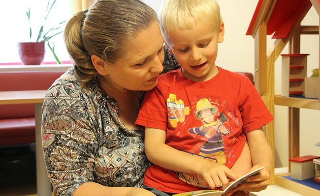 Mutter und Sohn lesen Buch / Caritas Socialis